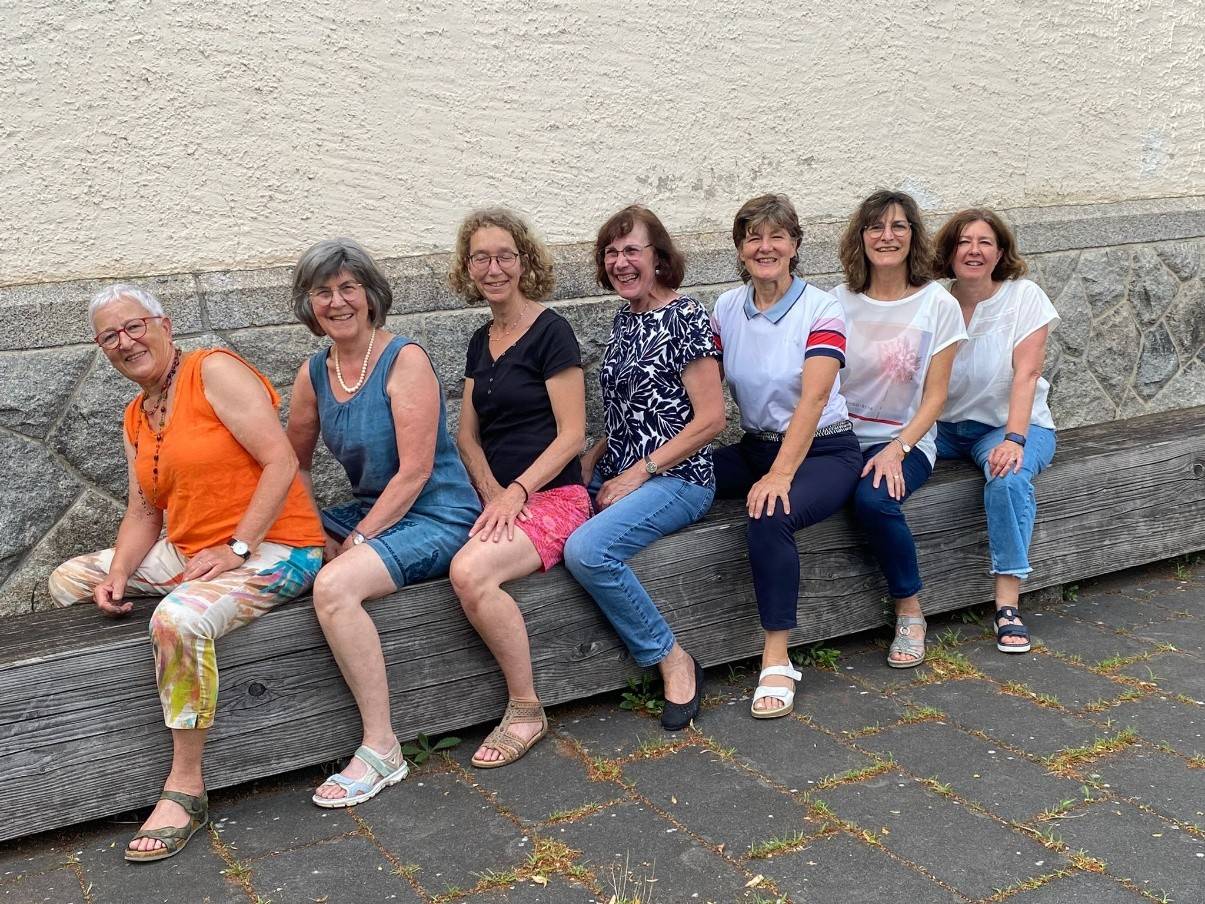 Evangelische und katholische Frauen vertiefen Zusammenarbeit - 7 Frauen sitzen auf einer Holzbank.jpg